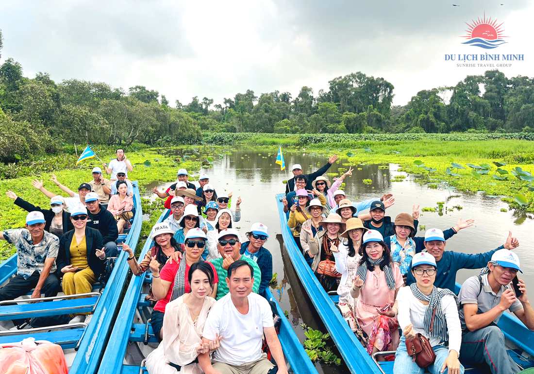 Đoàn khách Du Lịch Bình Minh ngồi xuồng máy tham quan kênh nước phủ bèo và sen ở rừng tràm Trà Sư An Giang