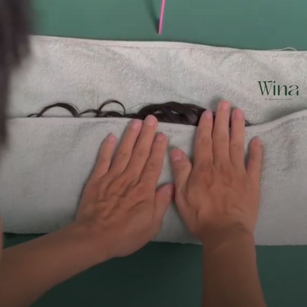 Dùng khăn bông mềm thấm nhẹ nhàng để loại bỏ nước thừa trên tóc giả