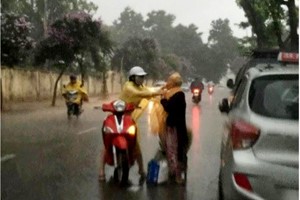 Có một cô gái dừng xe giữa đường mặc áo mưa cho cụ bà không quen biết ?
