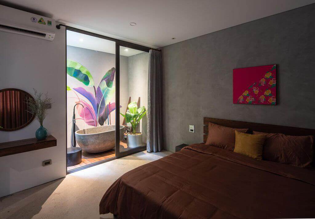 1 góc không gian phòng ngủ được kết hợp bởi tone màu xám của tường hiệu ứng bê tông và bồn tắm bê tông.