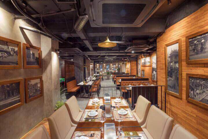 Toàn cảnh không gian nhà hàng với sự kết hợp của màu xám bê tông và màu cam gỗ.