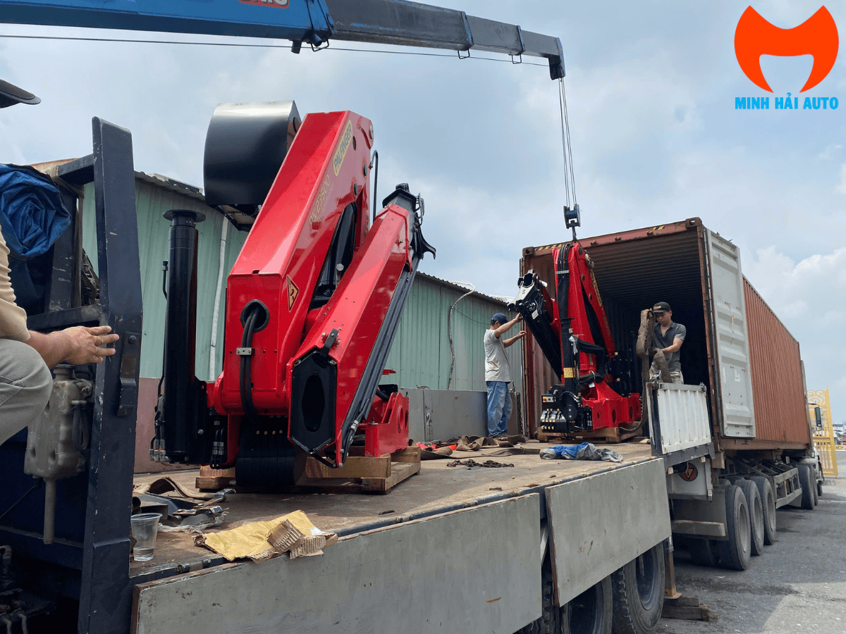 Cận cảnh cẩu robot Palfinger PK 15500 6 tấn đang hoạt động tại công trường xây dựng, nâng một pallet gạch.