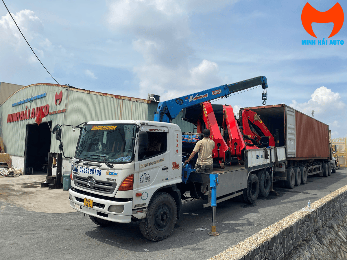 Cẩu gấp khúc Palfinger được gập gọn gàng phía sau cabin xe tải, nổi bật logo Palfinger trên thân cẩu.