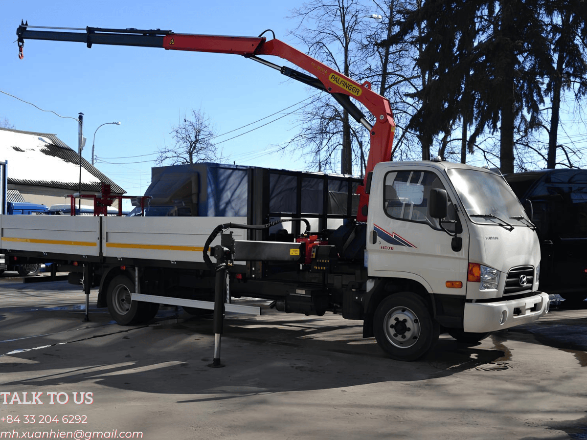 Toàn cảnh xe tải Hyundai HD78 màu trắng gắn cẩu gập Palfinger PK 8500 3 tấn, với cẩu được gấp gọn sau cabin tại bãi xe.