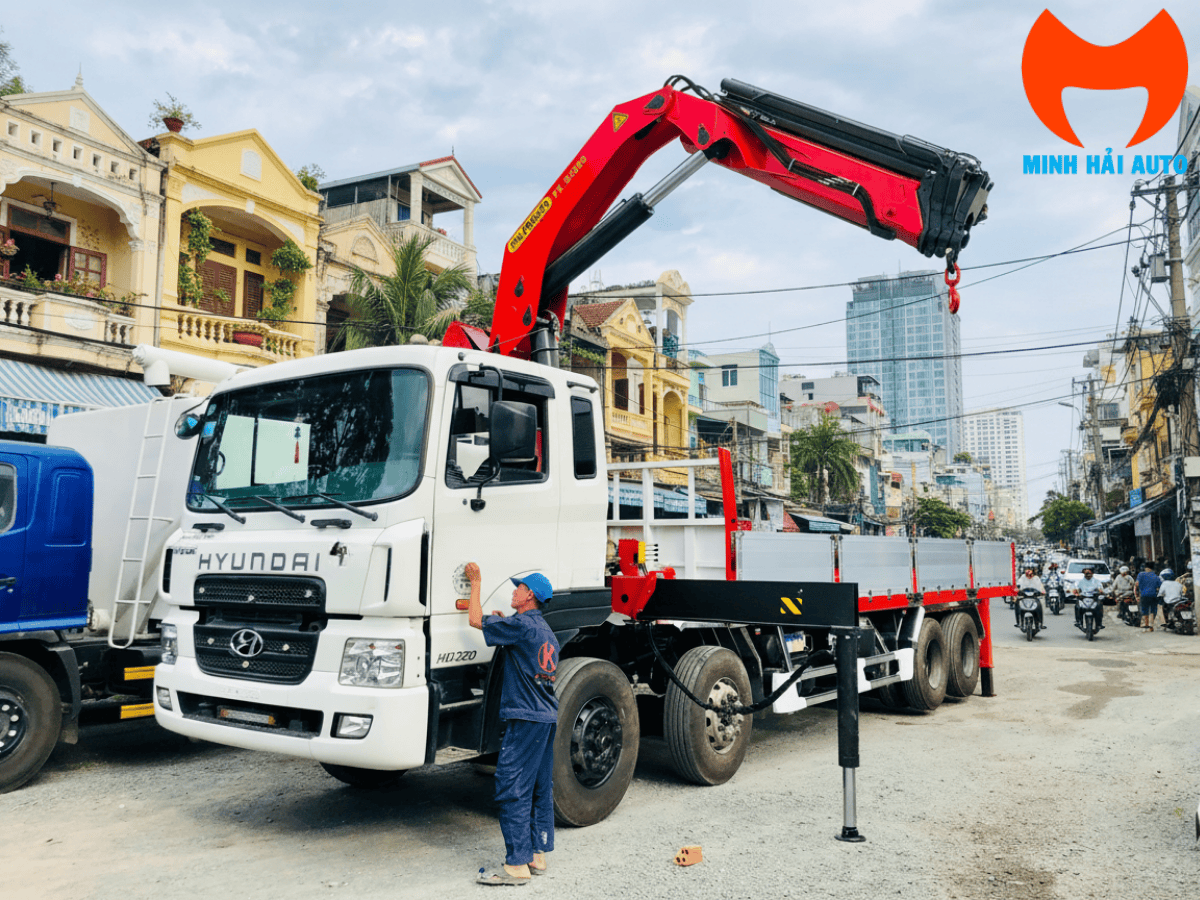 Ứng dụng xe cẩu HD320 Palfinger 12 tấn đang bốc dỡ máy móc công nghiệp nặng tại công trường xây dựng.