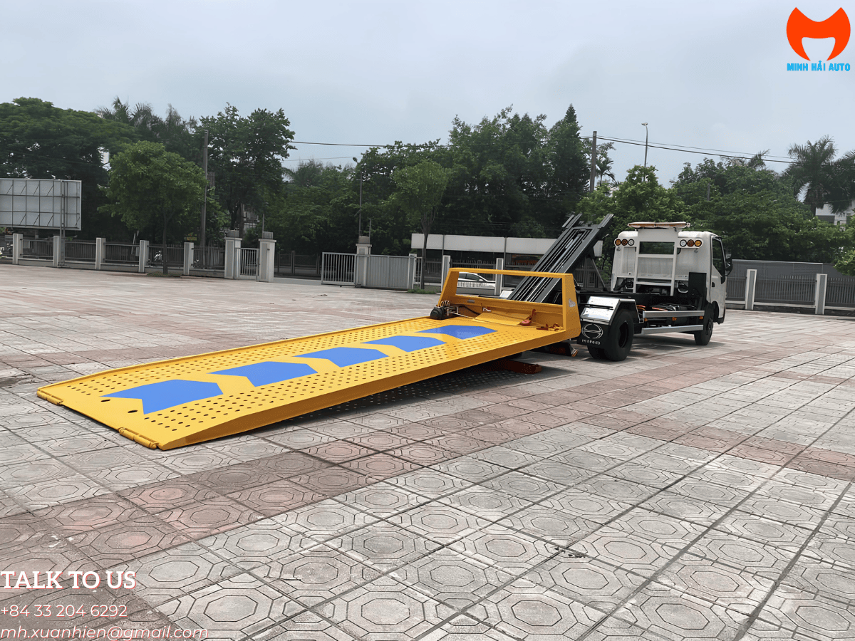 Xe cứu hộ Hino XZU720 sàn trượt màu trắng đang nâng chiếc xe thể thao màu đỏ lên sàn, thể hiện khả năng cứu hộ xe gầm thấp an toàn.