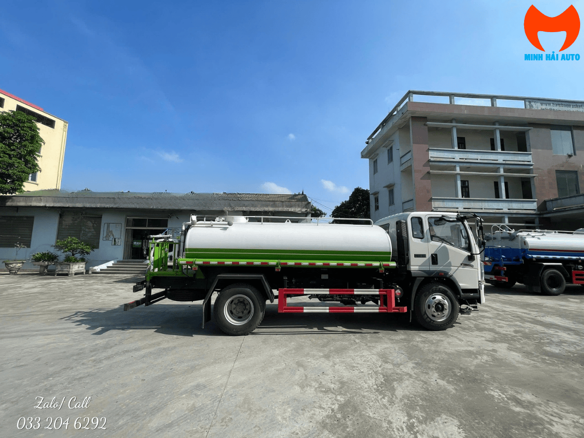 Xe xi téc phun nước rửa đường Hino 6 khối màu trắng đang hoạt động tưới cây xanh tại công viên trung tâm.
