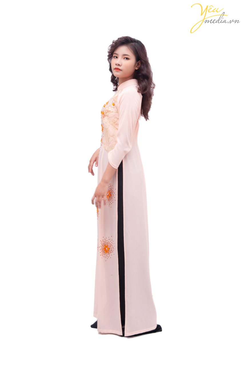 Bộ áo dài 68 truyền thống mang màu sắc hồng nhạt nhẹ nhàng - điểm thêm các đường nét màu cam sắc sảo và ấn tượng, là sự lựa chọn hàng đầu cho các cô dâu yêu thích màu sắc truyền thống, nhẹ nhàng.