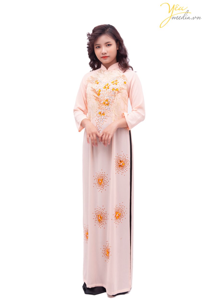 Bộ áo dài 68 truyền thống mang màu sắc hồng nhạt nhẹ nhàng - điểm thêm các đường nét màu cam sắc sảo và ấn tượng, là sự lựa chọn hàng đầu cho các cô dâu yêu thích màu sắc truyền thống, nhẹ nhàng.