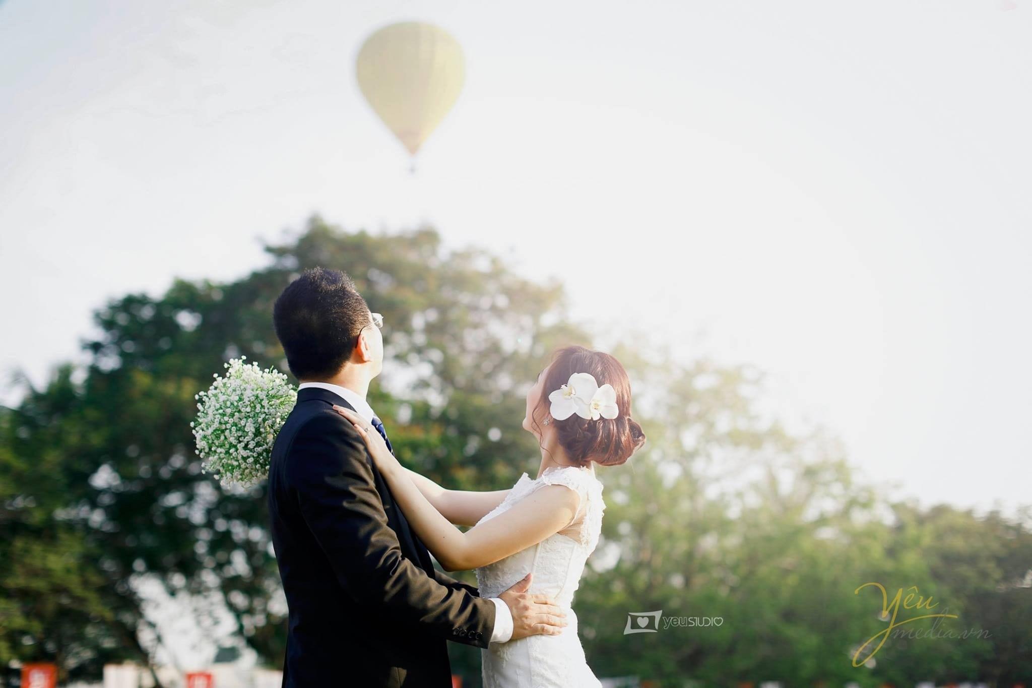 chú rể ôm eo cô dâu cùng nhìn về phía khinh khí cầu bay lên