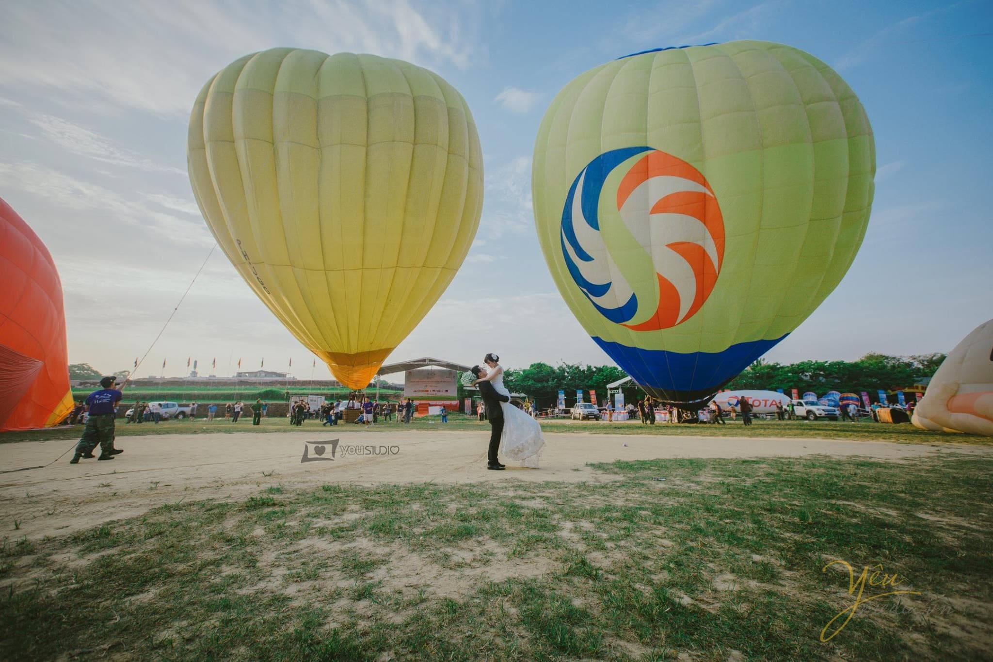 chú rể bế bổng cô dâu đứng trước khinh khí cầu