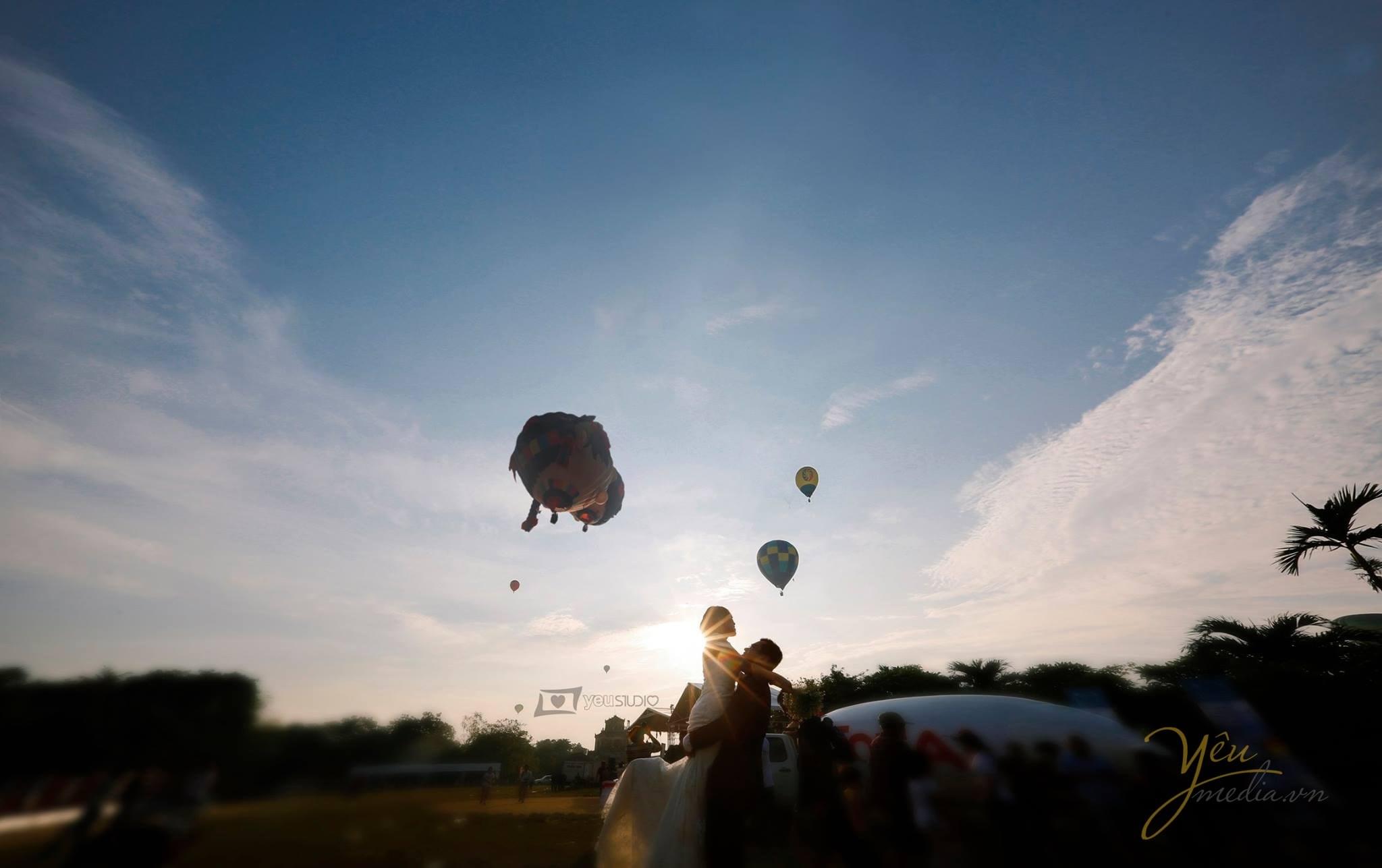 chú rể bế cô dâu nhìn theo khinh khí cầu bay lên trong nắng chiều