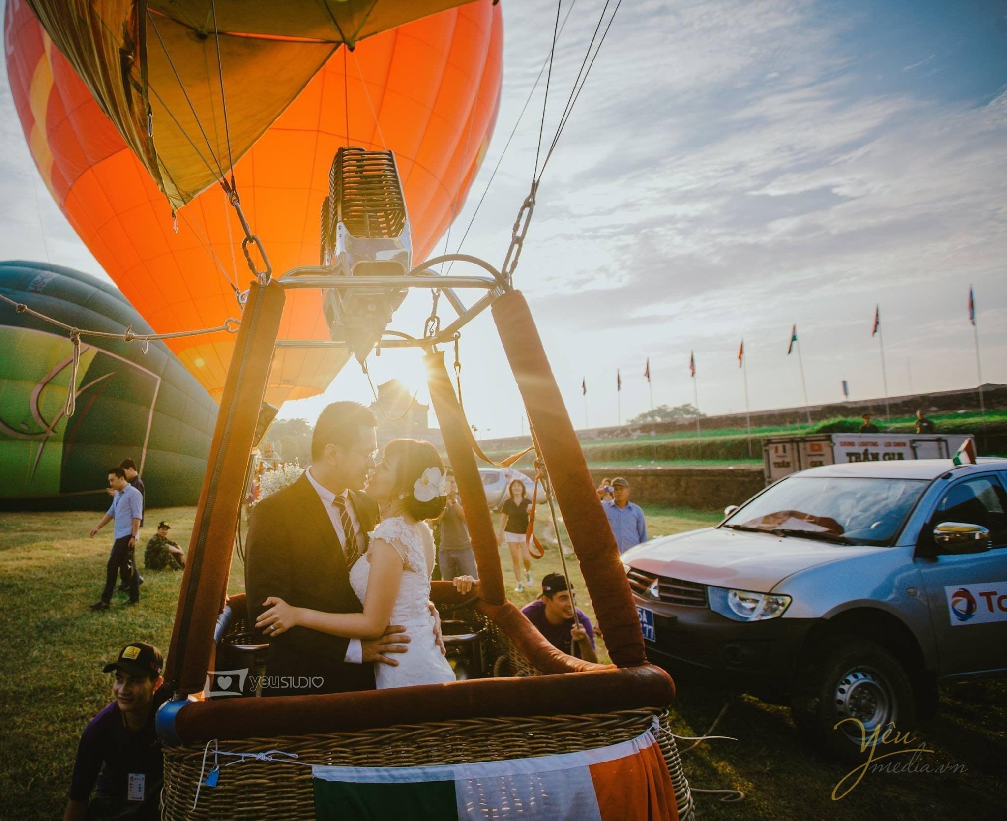 chú rể ôm eo cô dâu đứng trên khinh khí cầu