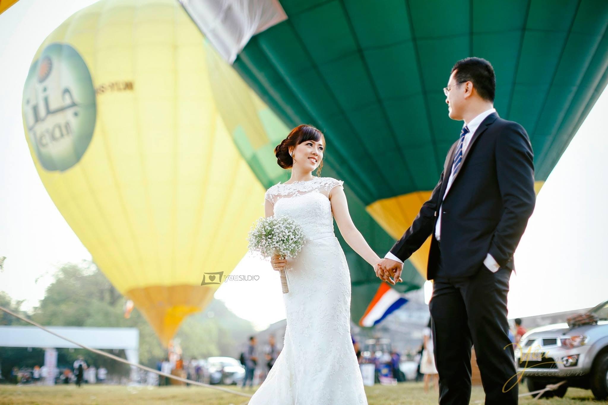 chú rể nắm tay cô dâu tình tứ trước khinh khí cầu