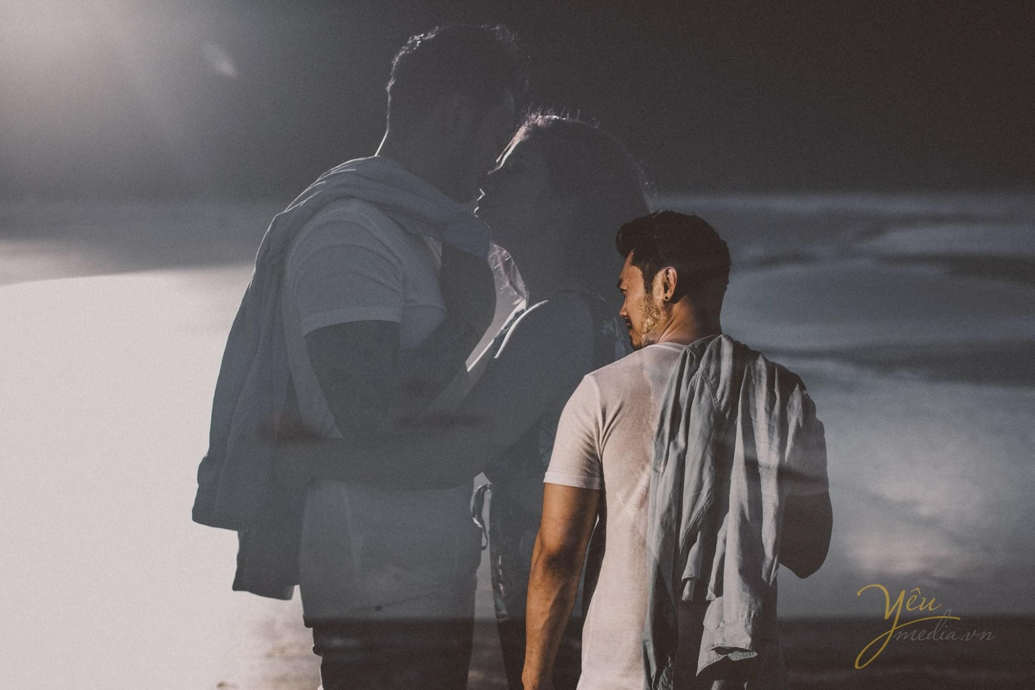 ảnh cưới chụp sau lưng chú rể in bóng lên màn hình chiếu ảnh 2 người ôm nhau