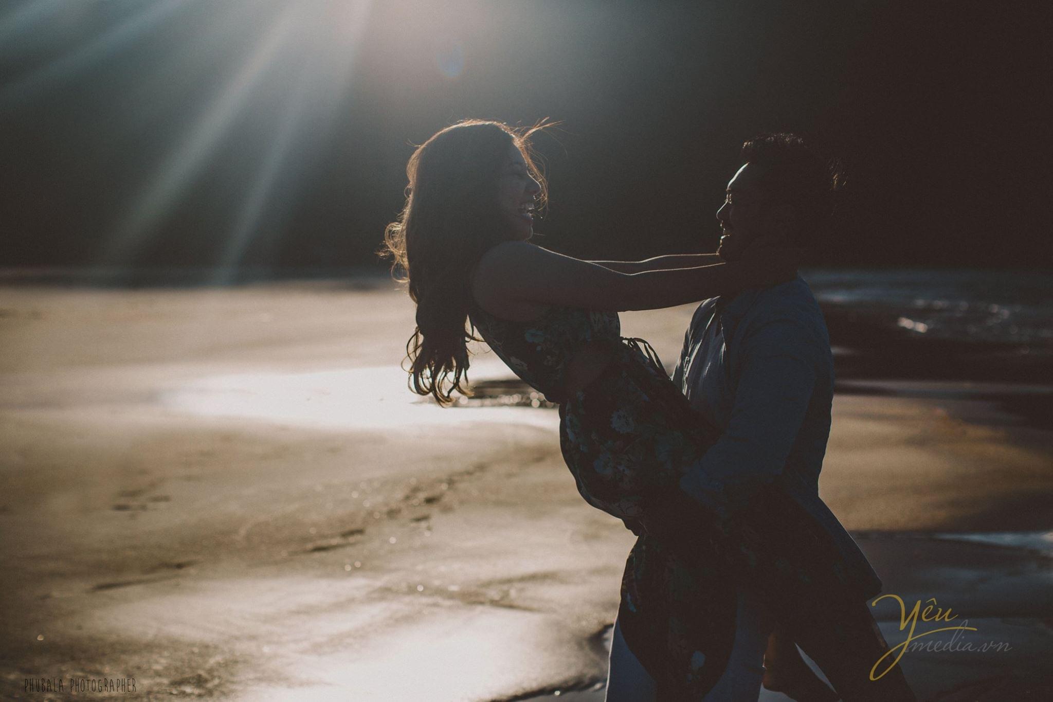 ảnh chú rể bế cô dâu ngả người trên biển hoàng hôn trên đầu