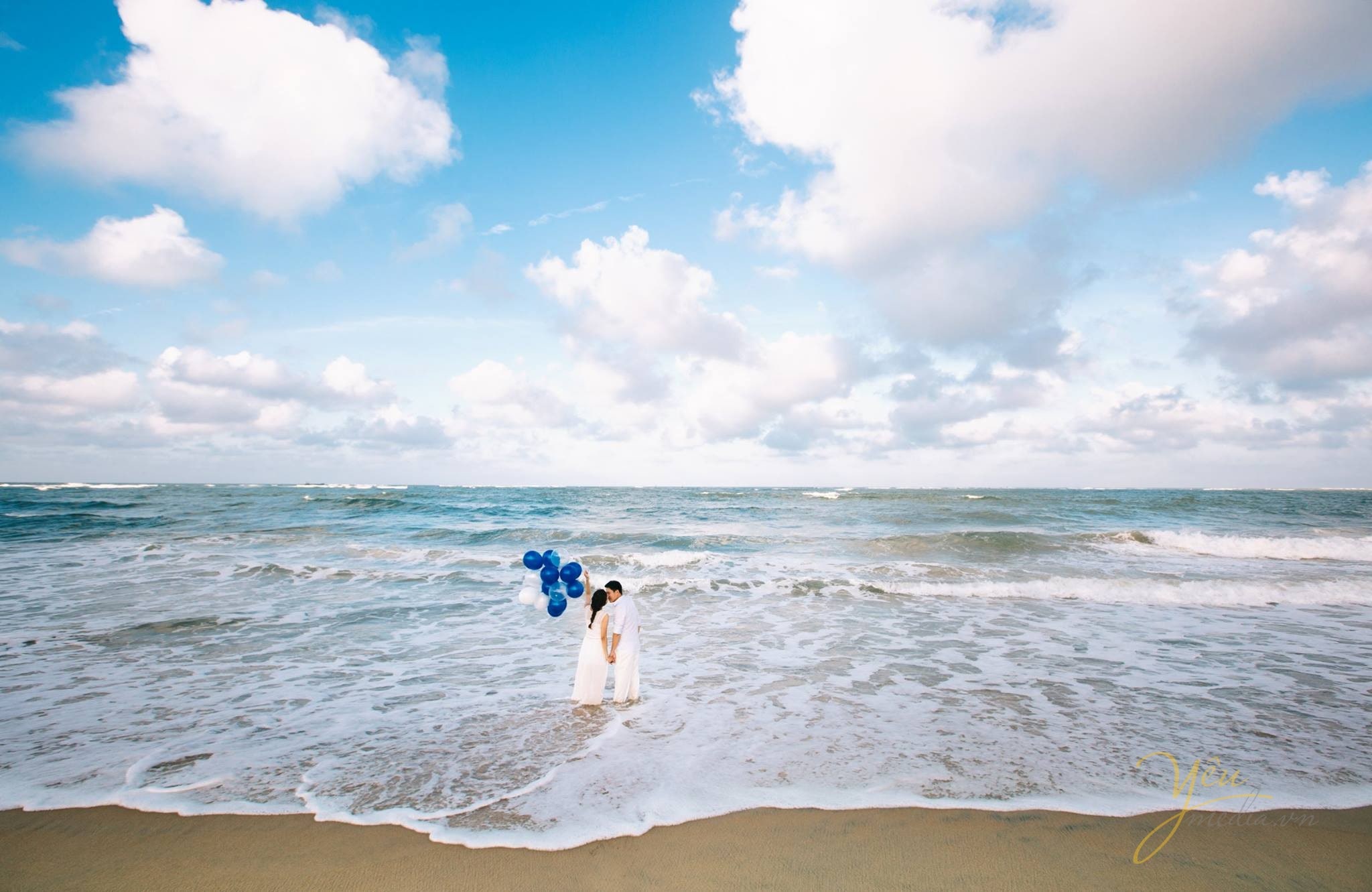 cô dâu chú rể nắm tay cầm bóng bay hướng ra biển