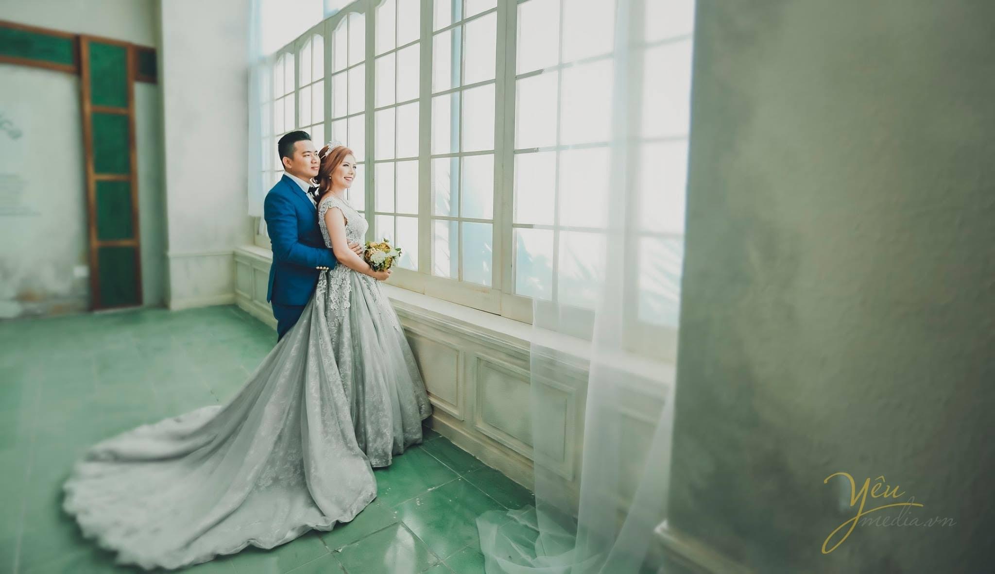 chú rể ôm phía sau lưng cô dâu cùng nhìn ra ngoài cửa