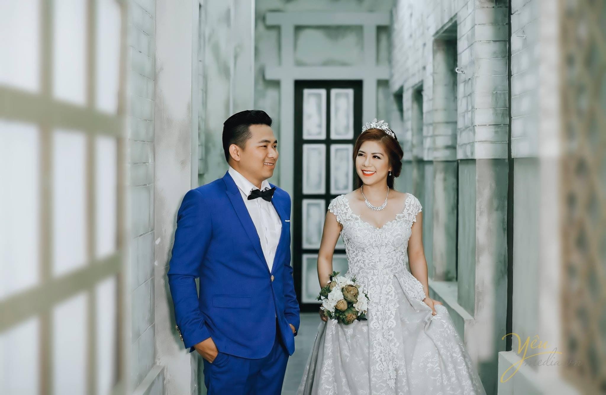 chú rể vest xanh cùng cô dâu bước đi qua sảnh lớn tòa nhà