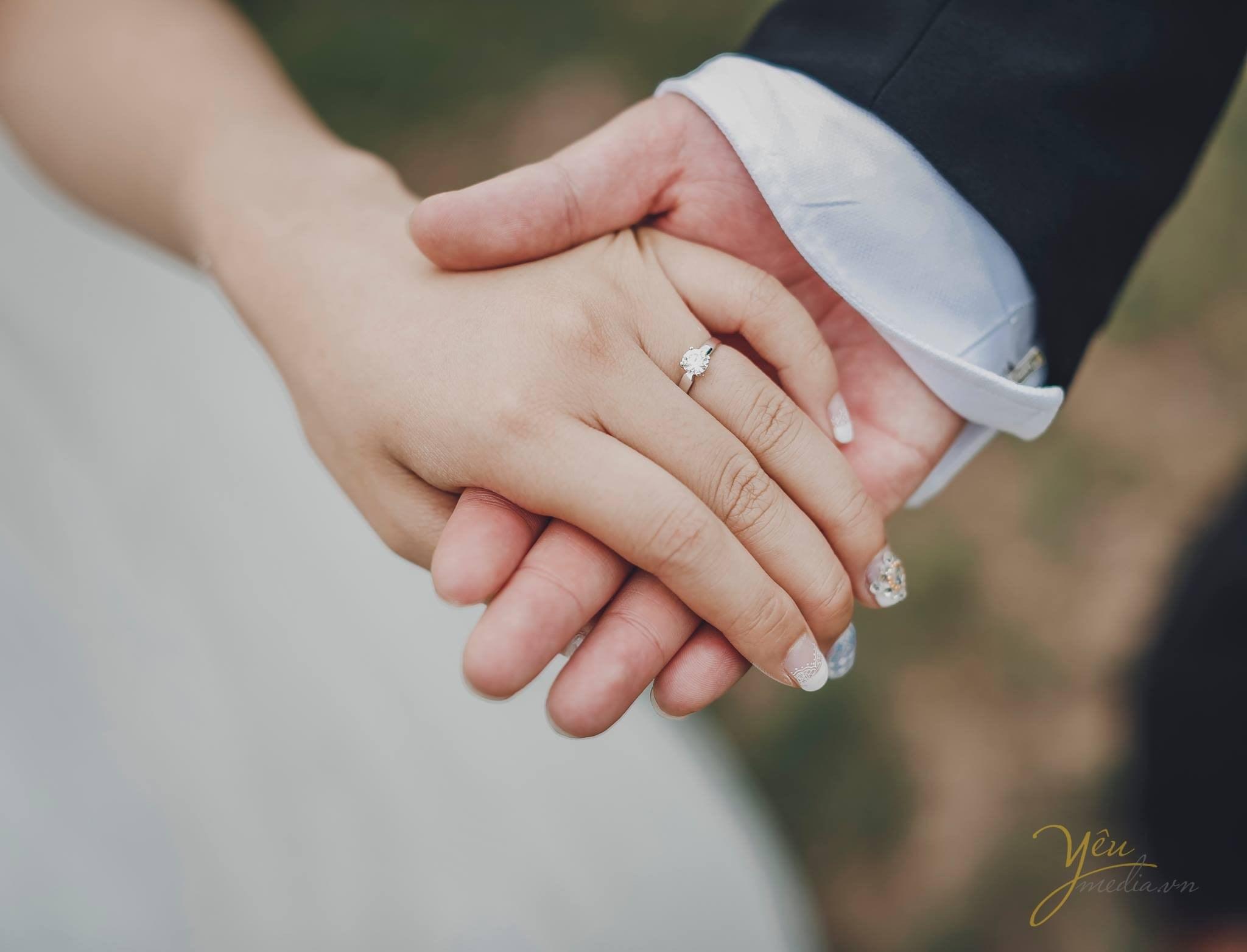 ảnh chụp tay chú rể và cô dâu cùng đeo nhẫn