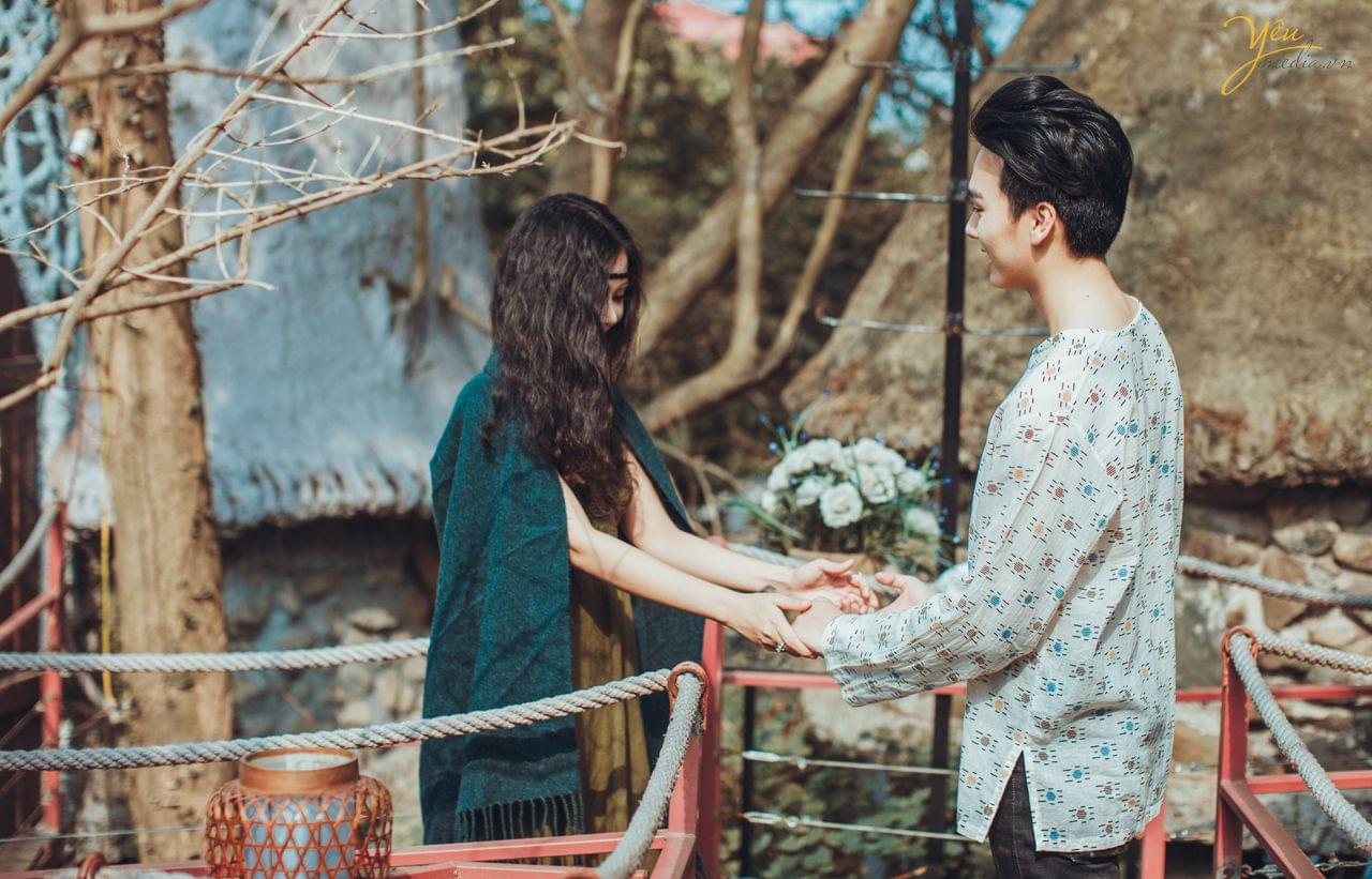 cô dâu chú rể nắm tay nhau trên cầu