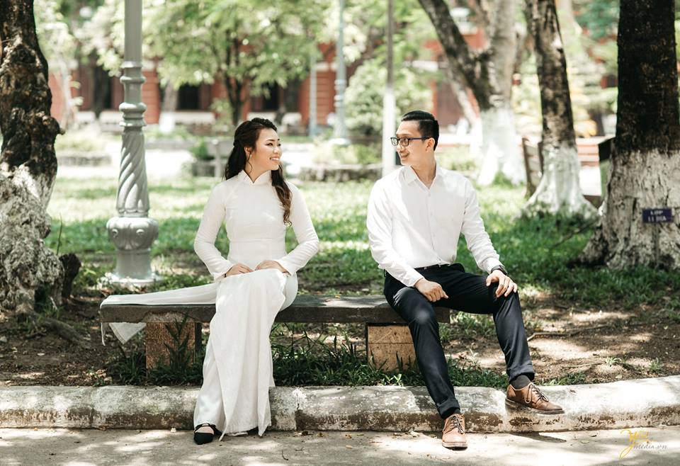 cô dâu chú rể ngồi nô đùa tại ghế đá sân trường