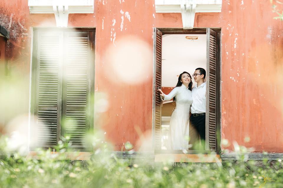 cô dâu chú rể đứng tại ô cửa sổ của trường