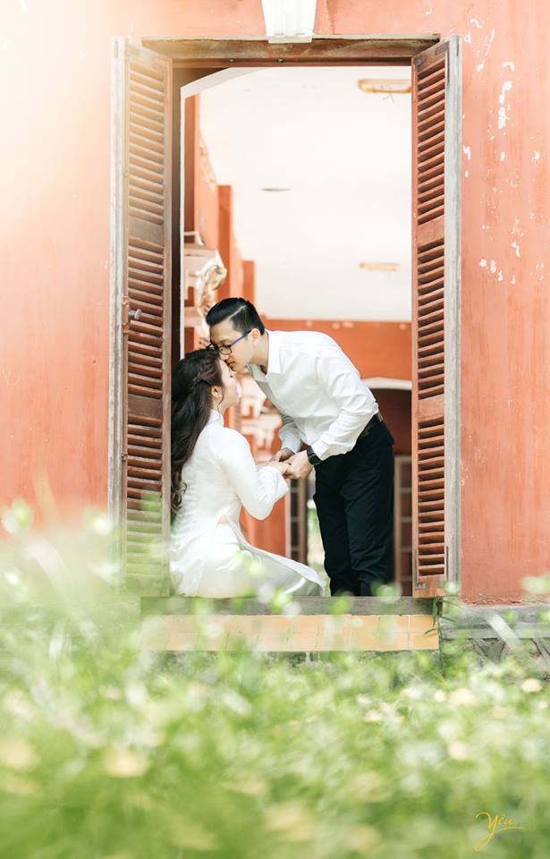 chú rể hôn trán cô dâu tại ô cửa sổ lớp học