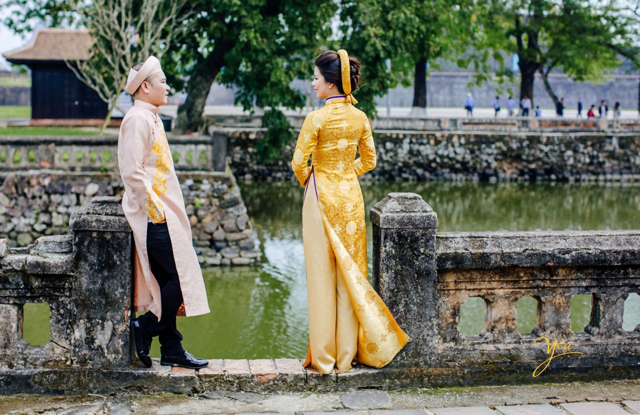 cô dâu chú rể đứng cạnh hồ nước