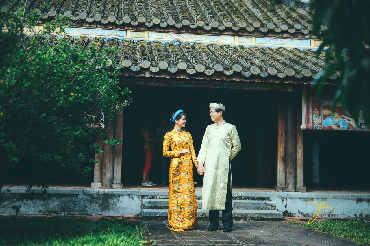 cô dâu chú rể nắm tay tình cảm mặc áo dài cổ truyền