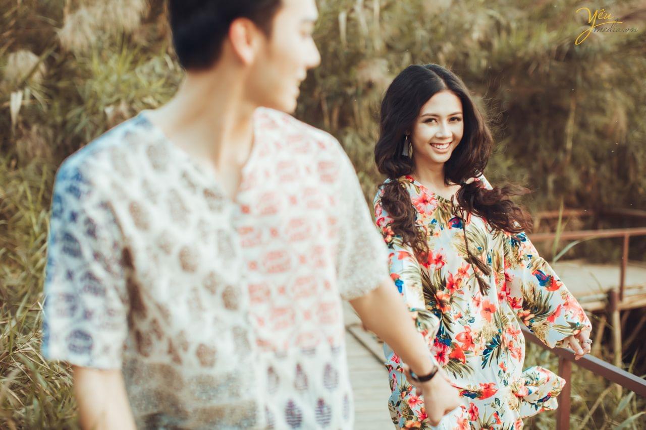 ảnh chụp qua vai chú rể cô dâu tươi cười chạy phía sau