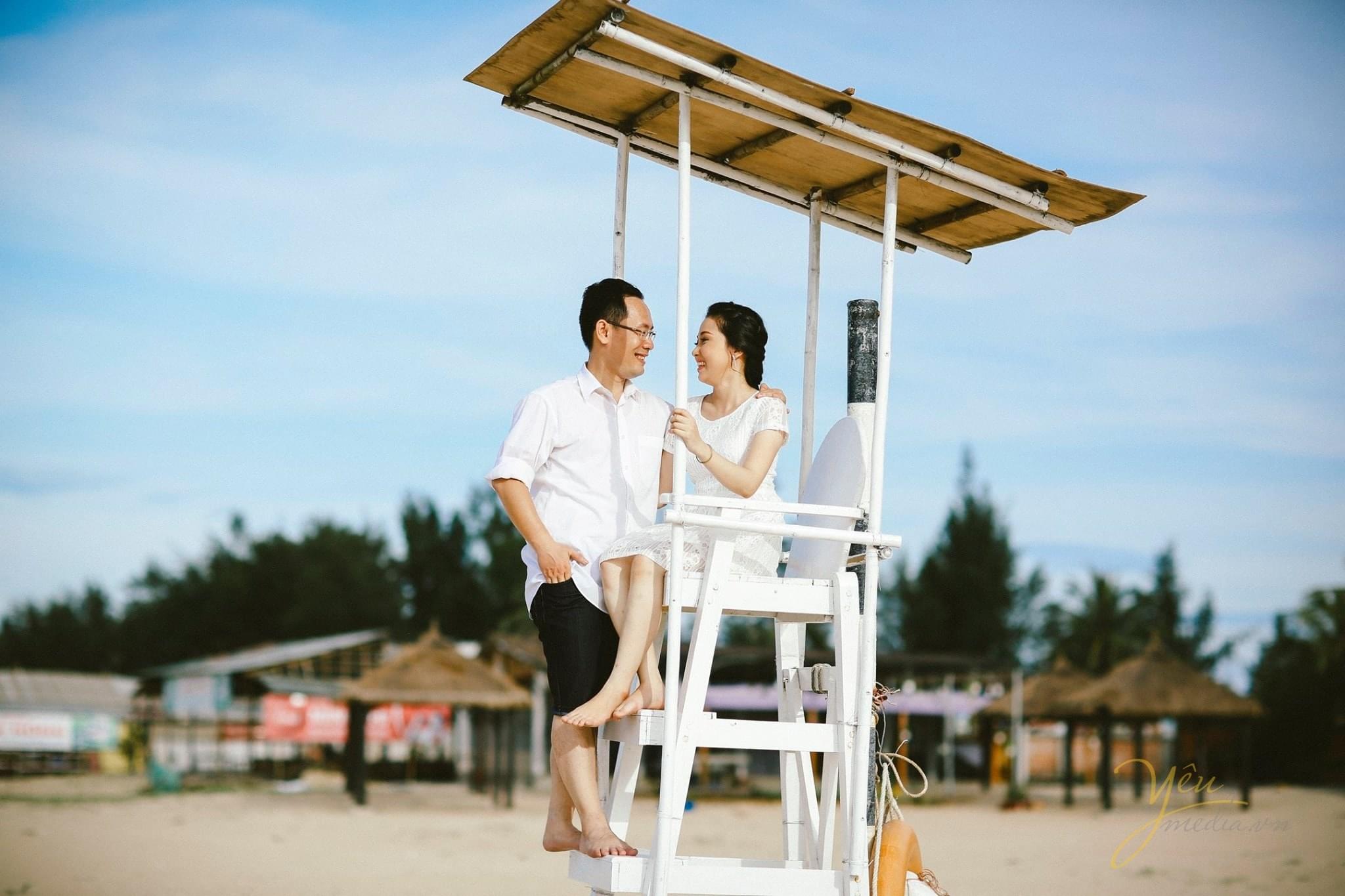 cô dâu chú rể ngồi trên chòi canh trên biển