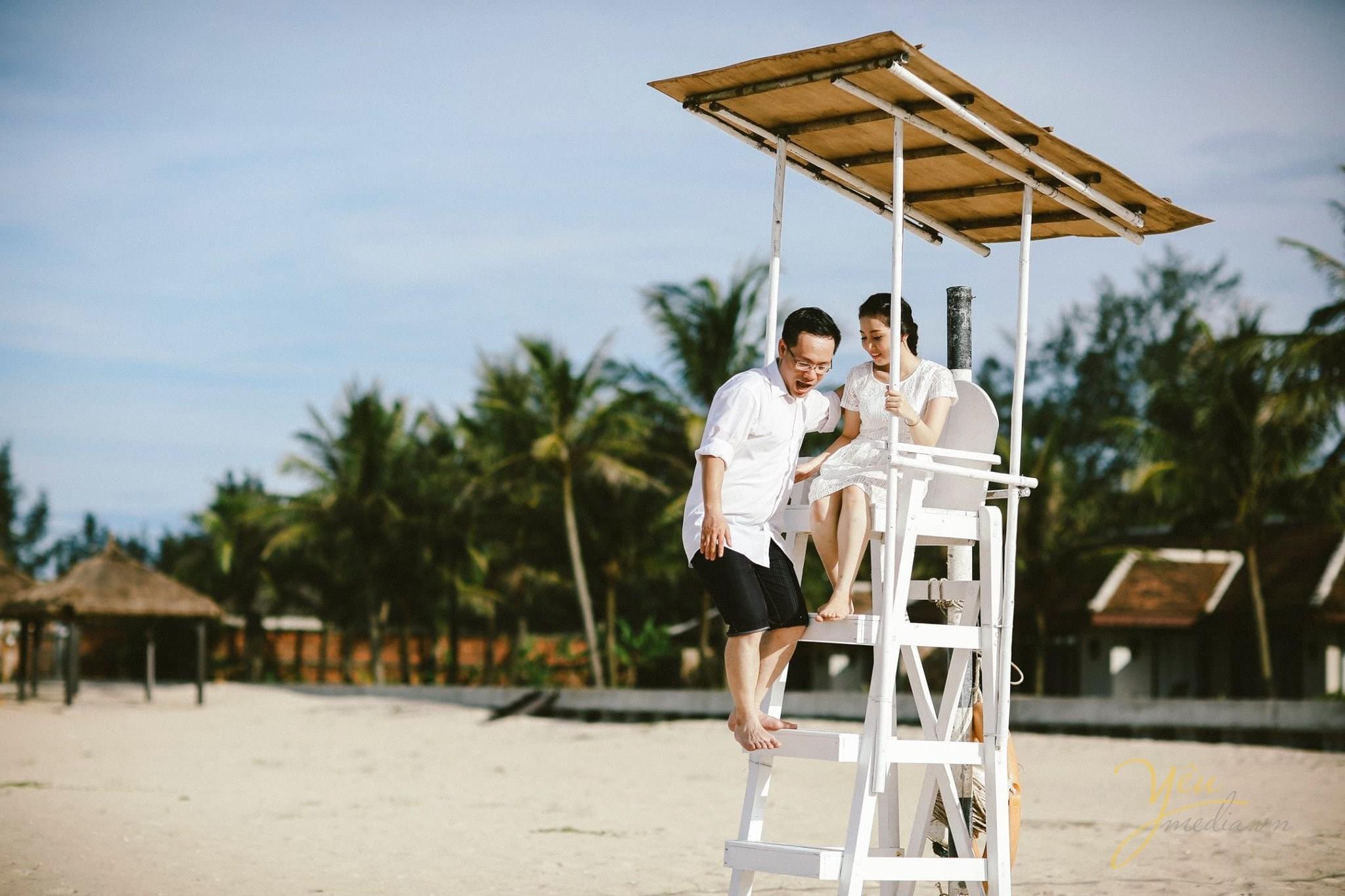 chú rể đỡ cô dâu xuống chòi canh trên biển