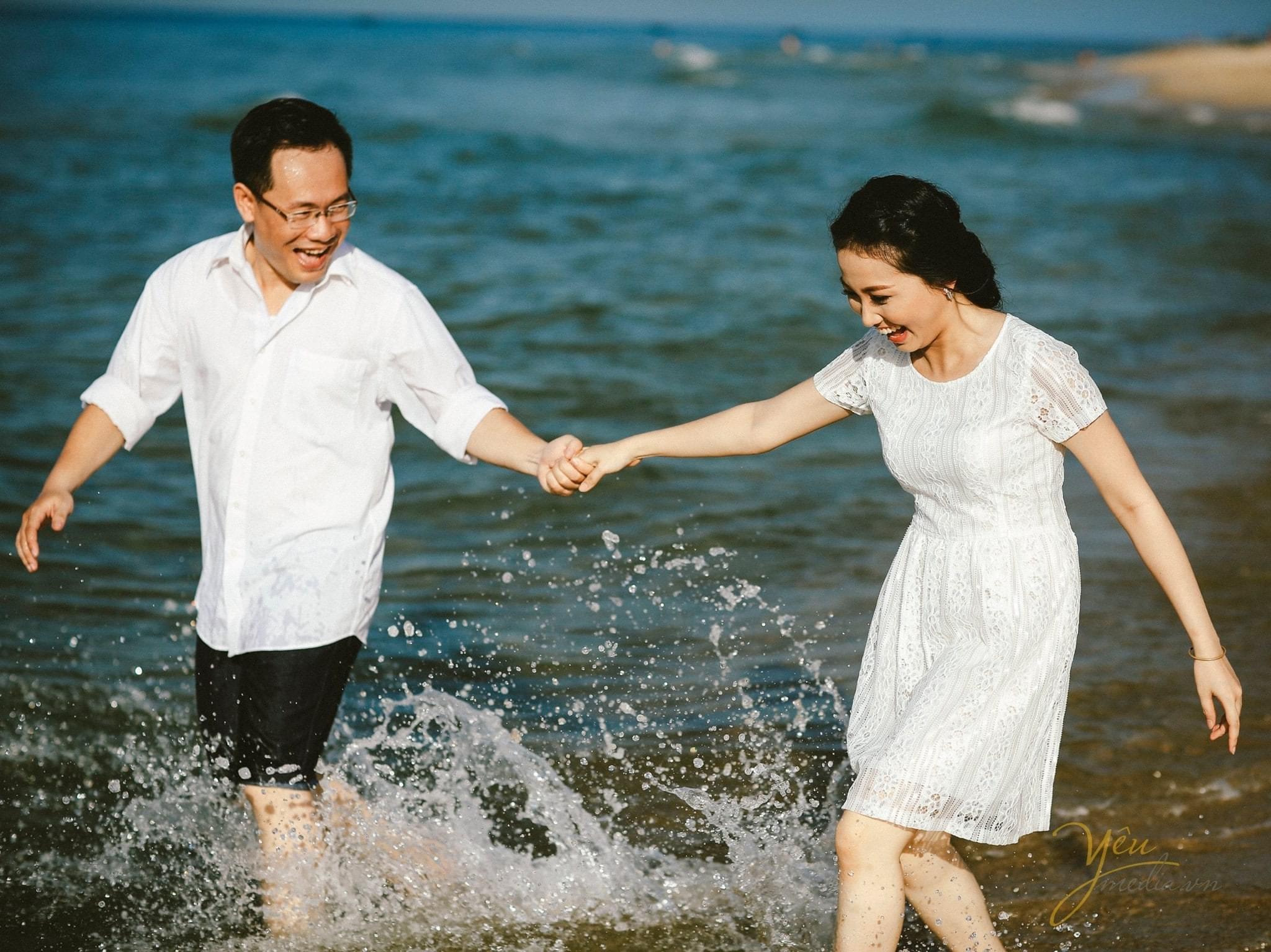 chú rể dắt tay cô dâu chạy trên bờ biển