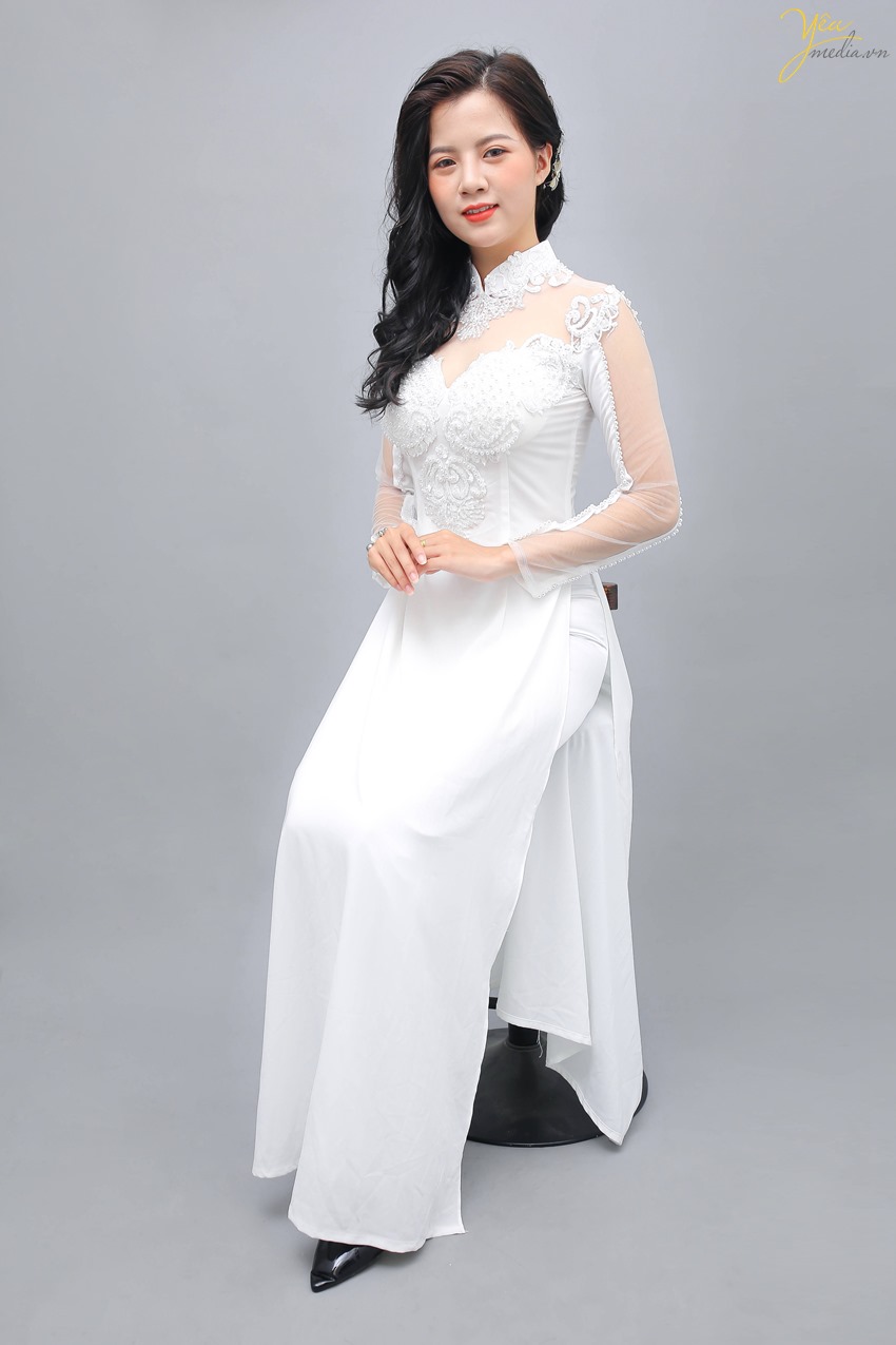 Áo dài trắng chưa bao giờ lỗi mốt. Vẻ đẹp dịu dàng, nền nã của chiếc áo dài trắng, đi cùng với chiếc quần lụa màu trắng luôn là lựa chọn hoàn hảo cho những cô nàng thích vẻ trong sáng. Từng đường nét thiết kế của chiếc áo dài đều được tính toán cẩn thận, hướng tới sự tinh tế. Chiếc cổ tàu nhẹ nhàng, khoe khéo chiếc cổ xinh xắn, giúp tôn được những nét đẹp nhẹ nhàng tiềm ẩn ở mỗi người con gái. Phía ngực của áo dài đính những đường ngọc trai hết sức sang trọng và quý phái, lớp ren mỏng trước ngực và phía sau mềm mại giúp chiếc áo dài thêm phần cuốn hút.