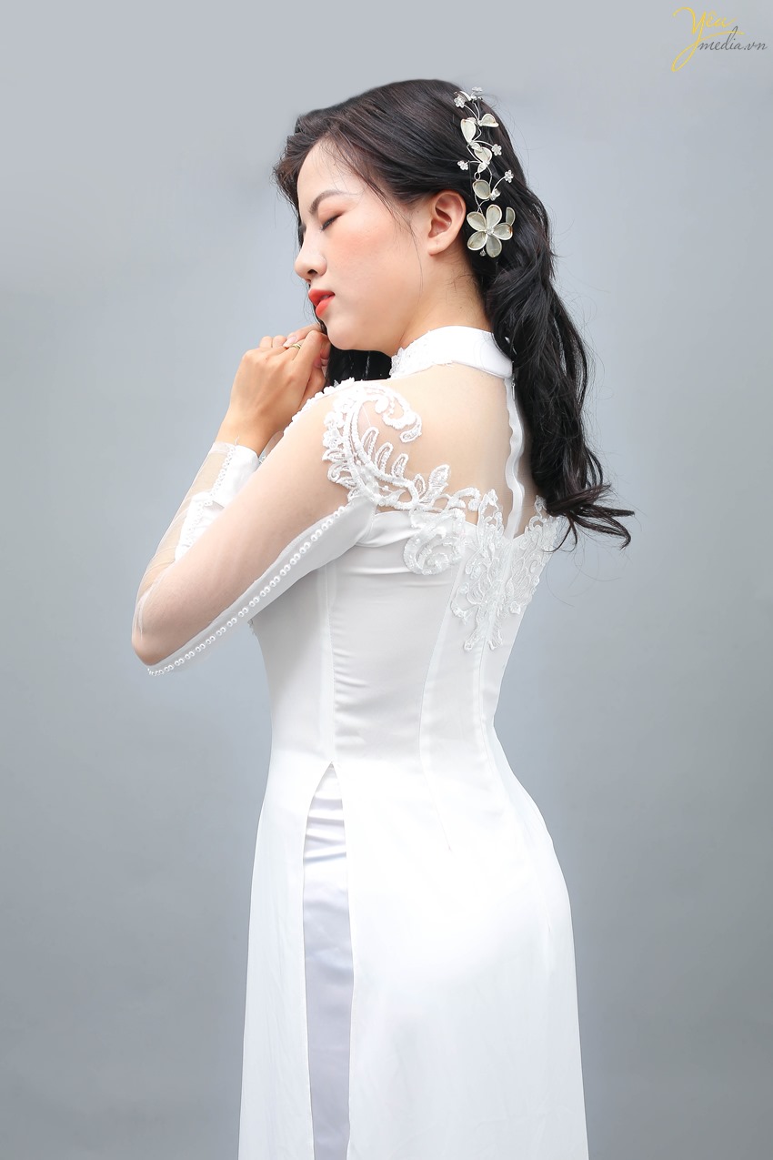 Áo dài trắng chưa bao giờ lỗi mốt. Vẻ đẹp dịu dàng, nền nã của chiếc áo dài trắng, đi cùng với chiếc quần lụa màu trắng luôn là lựa chọn hoàn hảo cho những cô nàng thích vẻ trong sáng. Từng đường nét thiết kế của chiếc áo dài đều được tính toán cẩn thận, hướng tới sự tinh tế. Chiếc cổ tàu nhẹ nhàng, khoe khéo chiếc cổ xinh xắn, giúp tôn được những nét đẹp nhẹ nhàng tiềm ẩn ở mỗi người con gái. Phía ngực của áo dài đính những đường ngọc trai hết sức sang trọng và quý phái, lớp ren mỏng trước ngực và phía sau mềm mại giúp chiếc áo dài thêm phần cuốn hút.
