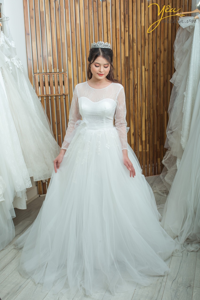 Váy cưới Camille với chất liệu ren sang chảnh nhưng vẫn kín đáo dịu dáng với lớp tay bồng nhẹ dài tay. Phần cúp ngực đầy đặn sẽ tôn vẻ duyên dáng cho mọi cô dâu của Yêu Media.