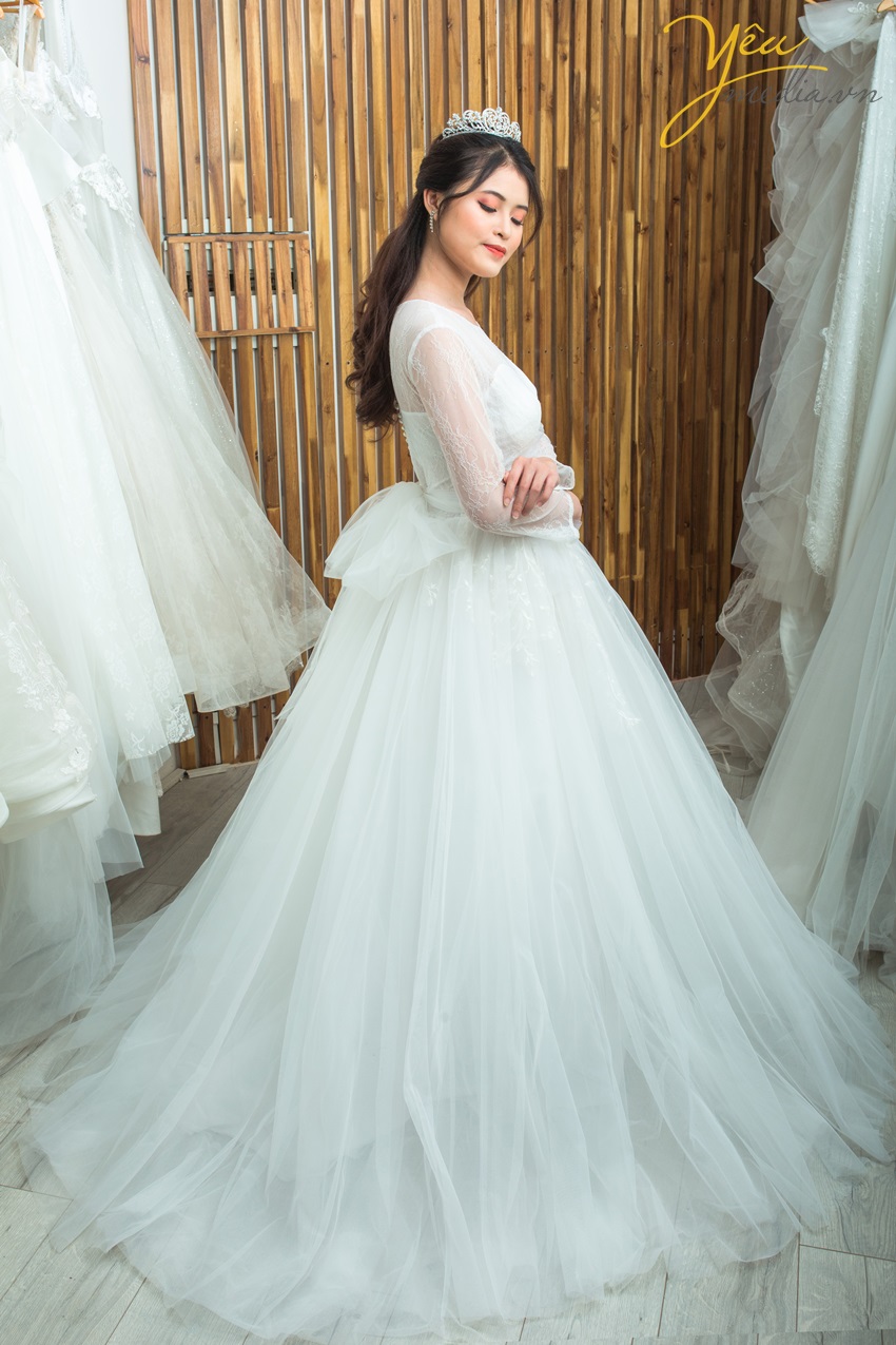Váy cưới Camille với chất liệu ren sang chảnh nhưng vẫn kín đáo dịu dáng với lớp tay bồng nhẹ dài tay. Phần cúp ngực đầy đặn sẽ tôn vẻ duyên dáng cho mọi cô dâu của Yêu Media.