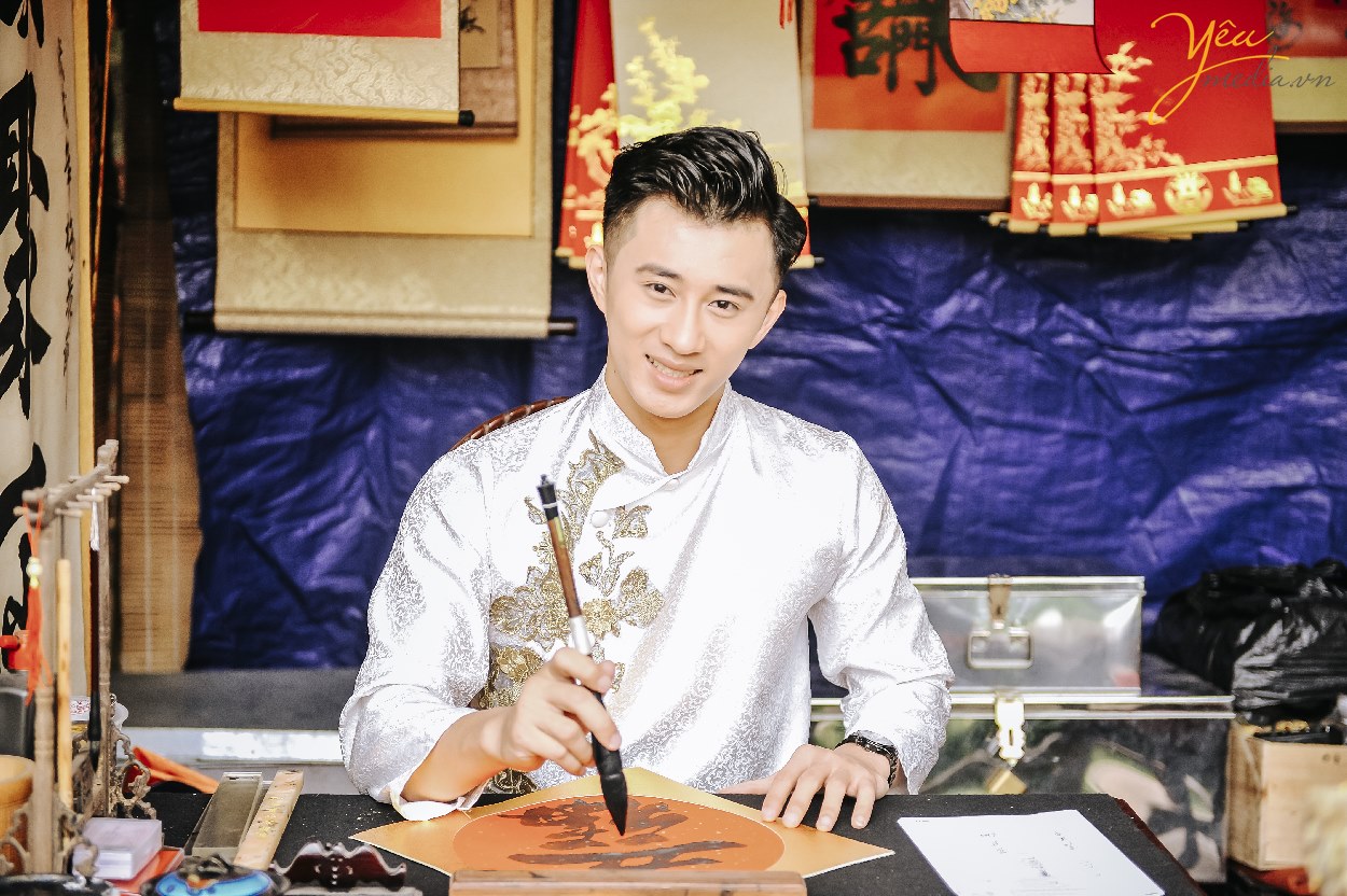 bạn nam mặc áo dài viết chữ nho trong văn miếu