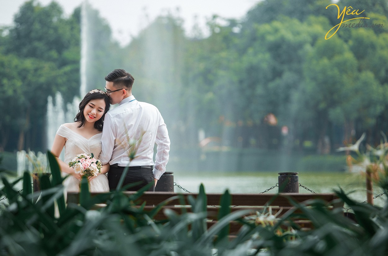 chụp ảnh cưới dựa đầu vào vai nhau bên vòi phun nước ở hồ