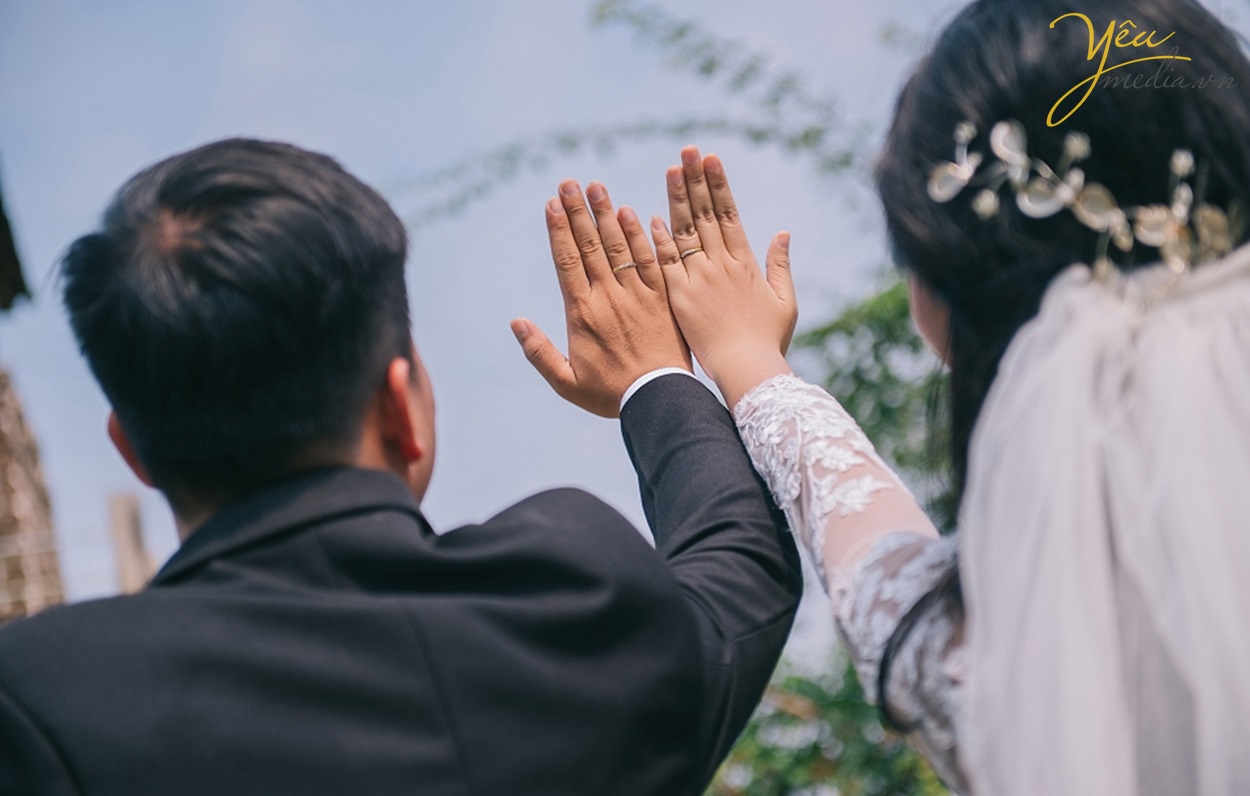 cô dâu chú rể giơ tay khoe nhẫn cưới