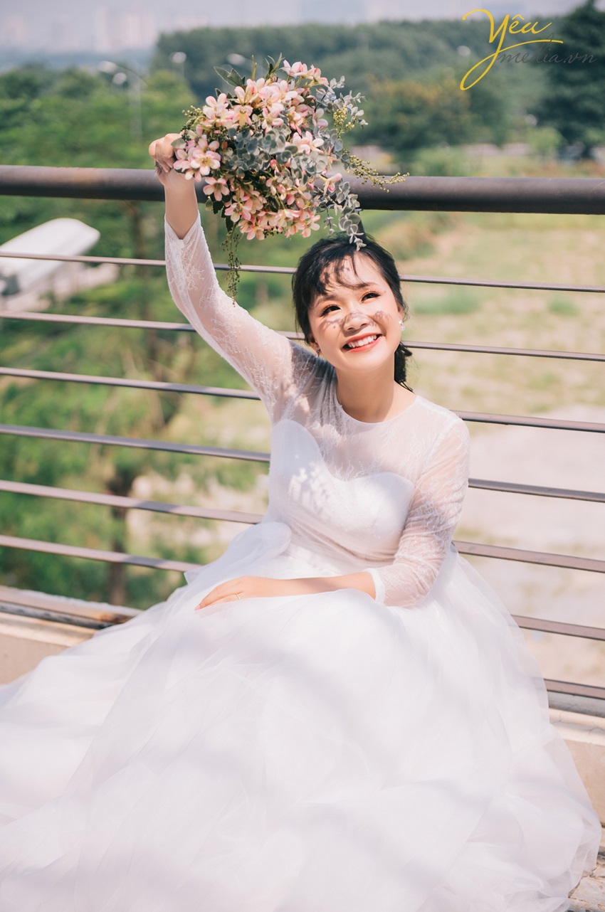 cô dâu xinh giơ bó hoa cưới cười tươi