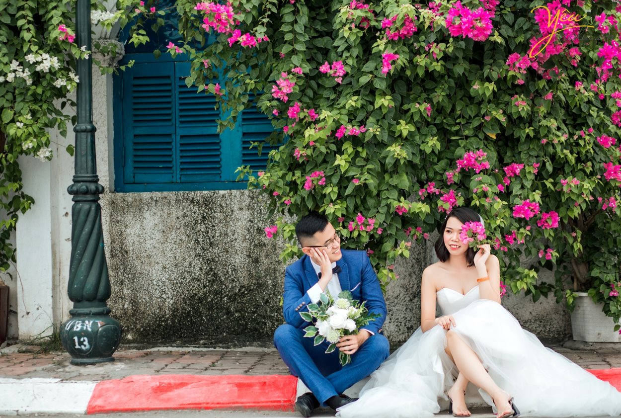 Chụp ảnh cưới ở con đường ven hồ và bến thuyền hồ tây ở Hà Nội được rất nhiều cặp đôi yêu thích. Ở Hồ tây có những góc chụp độc đáo và lãng mạn, đó là con đường lát gạch ven hồ Tây, đó là bến thuyền đầy thơ mộng. Chụp ảnh cưới ở Hồ Tây sẽ mang đến cho các cặp đôi những phút giây hạnh phúc và những bức ảnh vô cùng tuyệt đẹp. Hồ Tây là một trong những hồ rộng lớn và đẹp nhất Hà Nội. Bạn có thể đến với Hồ Tây bằng oto, xe máy, taxi hay xe buyt. Tuy nhiên HongKong Studio khuyên bạn nên đi tới đây bằng xe máy, vì nếu đi bằng oto hoặc taxi, bạn sẽ khó lòng cảm nhận được vẻ mênh mông bát ngát và không khí trong lành ở đây. Đến với Hồ Tây, bạn sẽ bắt gặp rất nhiều góc chụp đẹp bên con đường ven hồ và bến thuyền Hồ Tây. Chúng tuy không sang trọng như những khu nhà biệt thự với kiến trúc độc đáo, chúng cũng không xinh xắn, ngọt ngào như những ngôi nhà gỗ nằm bên giàn hoa tigon mà bạn sẽ bắt gặp khi đi dạo một vòng quanh hồ. Ở con đường ven hồ bên bến thuyền Hồ Tây toát lên vẻ mộc mạc những lại vô cùng quyến rũ. Bạn sẽ không ít hơn một lần tưởng tượng đang đi dưới con đường tình yêu như trong những bộ phim tình cảm Hàn Quốc.