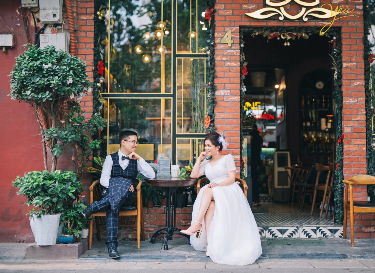 Trời nắng là thế nhưng lại không hề nóng tí nào đâu bạn nhé. Bởi những tán lá xanh mơn mởn kia đã là những chiếc ô kỳ diệu xua đi cái nắng hè oi ả các bạn ạ. Chính vì vậy mà nơi đây là không gian lý tưởng cho những buổi cắm trại cùng bạn bè. Các bạn có thể mang đến đây những đồ ăn nhẹ cùng một chiếc thảm lớn để dã ngoại và tổ chức những buổi picnic, team buidling ngoài trời cũng vô cùng dễ chịu. Còn điều gì tuyệt hơn là được cùng bạn bè trốn khỏi khói bụi thành phố sau một tuần học tập và làm việc mệt mỏi, được đến một không gian tràn ngập trong sắc màu của cỏ cây hoa lá, thả tâm hồn thư giãn cho đến khi bao mệt mỏi biến tan, cùng nhau trò chuyện, cùng kể cho nhau nghe những điều thú vị, cùng nhau cười giòn tan. Khi ấy bạn sẽ thực sự rời xa những ồn ào, náo nhiệt nơi thành đô, thỏa sức hòa mình cùng thiên nhiên kỳ diệu.    Yêu Media xin giới thiệu với bạn bộ ảnh mà ekip đã thực hiện cho cặp đôi Vũ - Phượng tại vườn nhãn và tại khu nhà thờ lớn - bờ hồ ở Hà Nội.