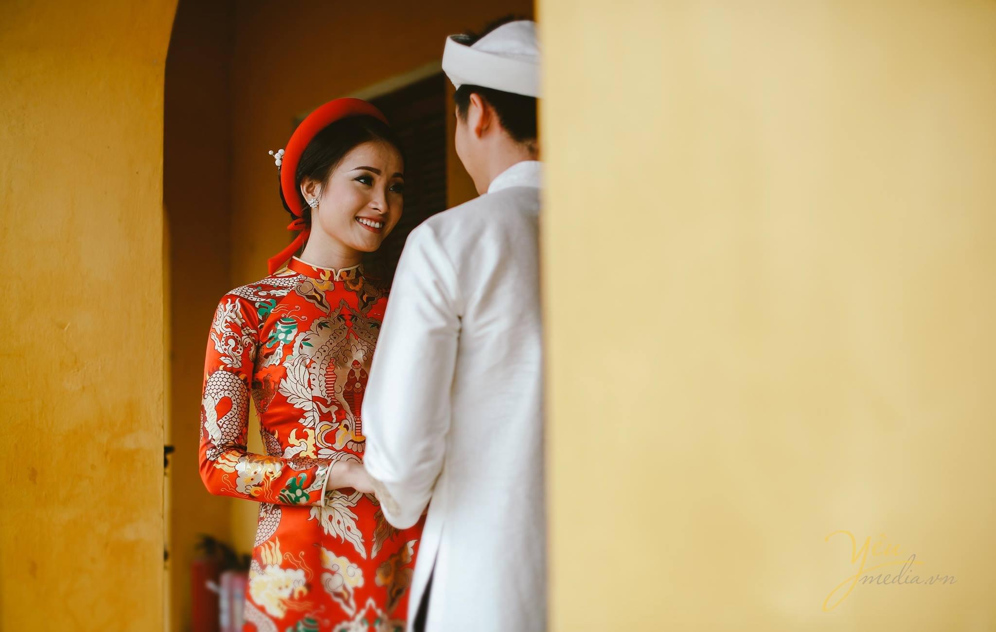 ảnh cưới áo dài gấm đỏ cô dâu chú rể nhìn nhau tình tứ