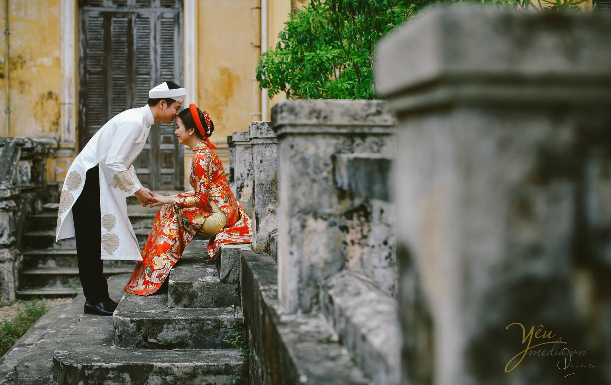 ảnh cưới chú rể mặc áo dài cổ truyền hôn trán cô dâu