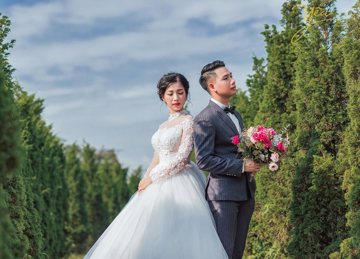 chụp ảnh cưới theo tư thế dựa lưng vào nhau đứng trong khu vườn