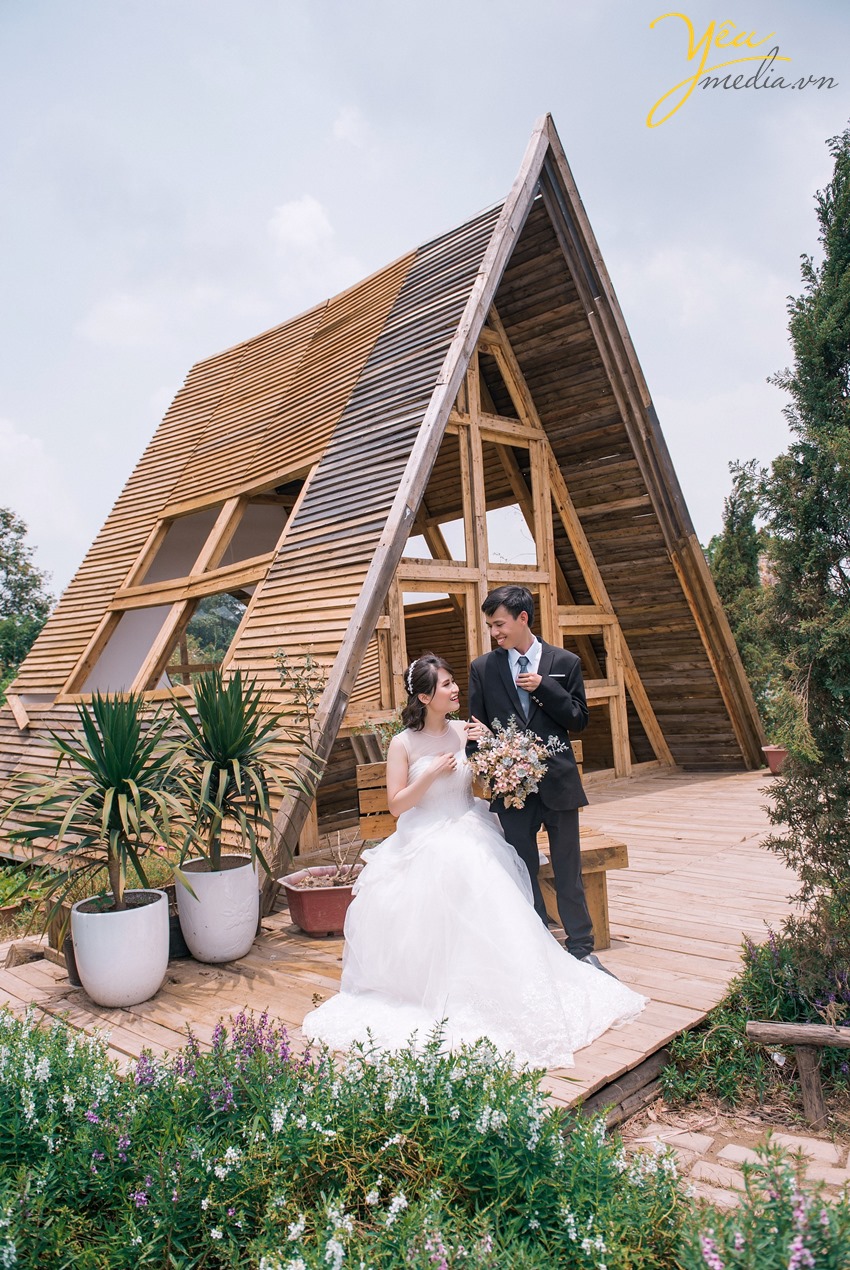 cô dâu chú rể chụp ảnh trước ngôi nhà gỗ