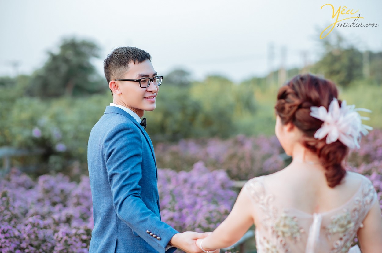 chú rể dắt tay cô dâu đi trong vườn khi chụp hình cưới