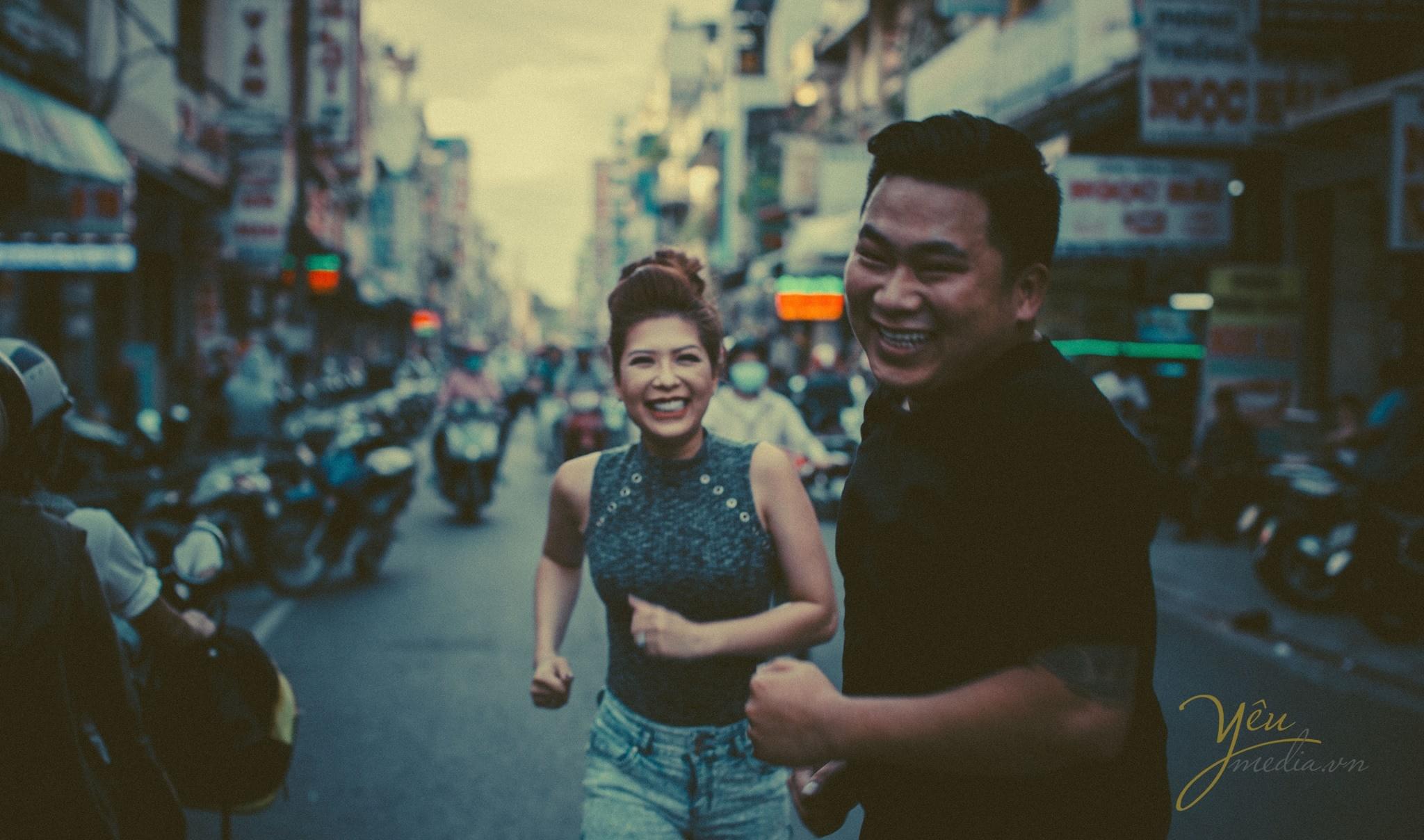 cô dâu chú rể cùng chạy trên đường cười tươi